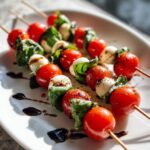 Close-up of several Caprese skewers featuring cherry tomatoes, mozzarella balls, and basil, drizzled with balsamic glaze.