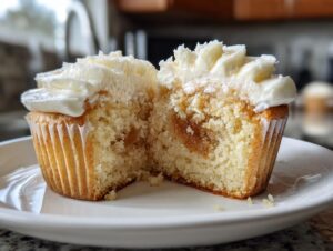 Close-up of an Apple pie cupcakes cut in half, showing the moist cake, apple filling, and white frosting.