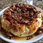 Close-up of a whole wheel of baked brie wrapped in pastry, topped generously with honey and pecans.