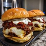 Two juicy Buldak smash burgers piled high with spicy sauce, melted white cheese, and a creamy topping on brioche buns.
