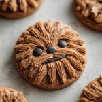 Close-up of a decorated gingerbread cookie resembling Chewbacca, featuring piped brown frosting for fur.