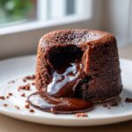 A decadent Chocolate lava cake with warm, molten chocolate oozing out onto a white plate.