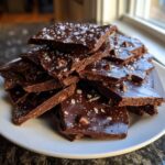 A stack of broken pieces of rich, dark Double chocolate brownie cookie bark sprinkled with flaky sea salt.