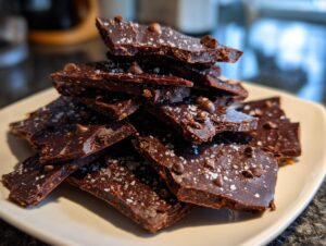 A stack of broken pieces of rich, dark Double chocolate brownie cookie bark sprinkled with sea salt and chocolate chips.