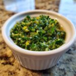 Close-up of bright green, chunky Mint gremolata mixed with lemon zest in a small white bowl.