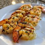 Close-up of perfectly cooked Garlic Herb Grilled Shrimp Skewers glistening with marinade on a white plate.