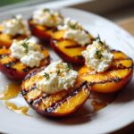 Close-up of grilled nectarines topped with burrata cheese, drizzled with honey, and garnished with thyme.