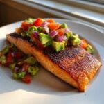 A beautifully seared fillet of grilled salmon topped generously with fresh avocado salsa.
