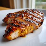 Close-up of perfectly cooked, sliced Honey mustard grilled chicken breast with a glossy, whole-grain mustard glaze.