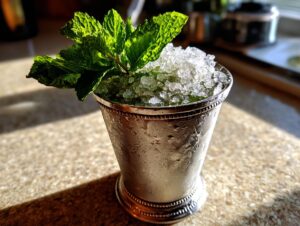 A classic Mint Julep cocktail served in a frosted silver julep cup, heavily garnished with fresh mint.