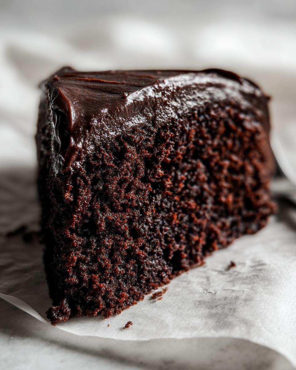 Close-up of a rich, dark slice of Devil's food cake showing its moist crumb and glossy chocolate frosting.