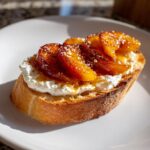 Close-up of a single peach burrata crostini topped with caramelized peaches and honey.