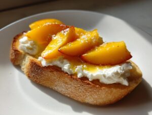 Close-up of a single Peach burrata crostini featuring toasted bread, creamy burrata, sliced peaches, and a drizzle of honey.