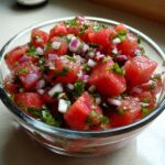 Close-up of vibrant Watermelon salsa featuring diced watermelon, red onion, and cilantro in a clear glass bowl.