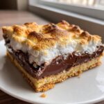 A square serving of Sheet pan smores with a toasted marshmallow top, melted chocolate center, and graham cracker crust.