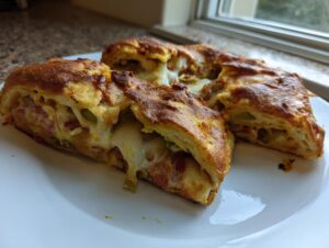 Close-up of sliced Garbage bread recipe showing melted cheese, pepperoni, and peppers inside a golden crust.