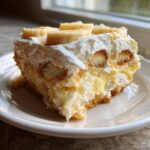 A decadent slice of Southern banana pudding layered with vanilla wafers, creamy custard, and topped with whipped cream and banana slices.