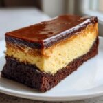 A perfect slice of Chocoflan showing three distinct layers: dark chocolate cake base, creamy flan center, and glossy caramel topping.